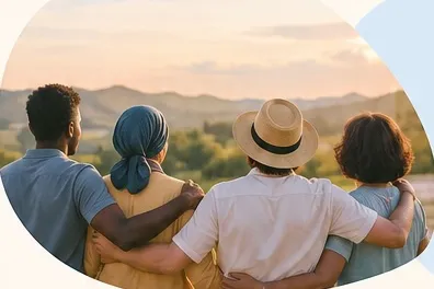 Four friends standing arm in arm, looking out over hills at sunset.